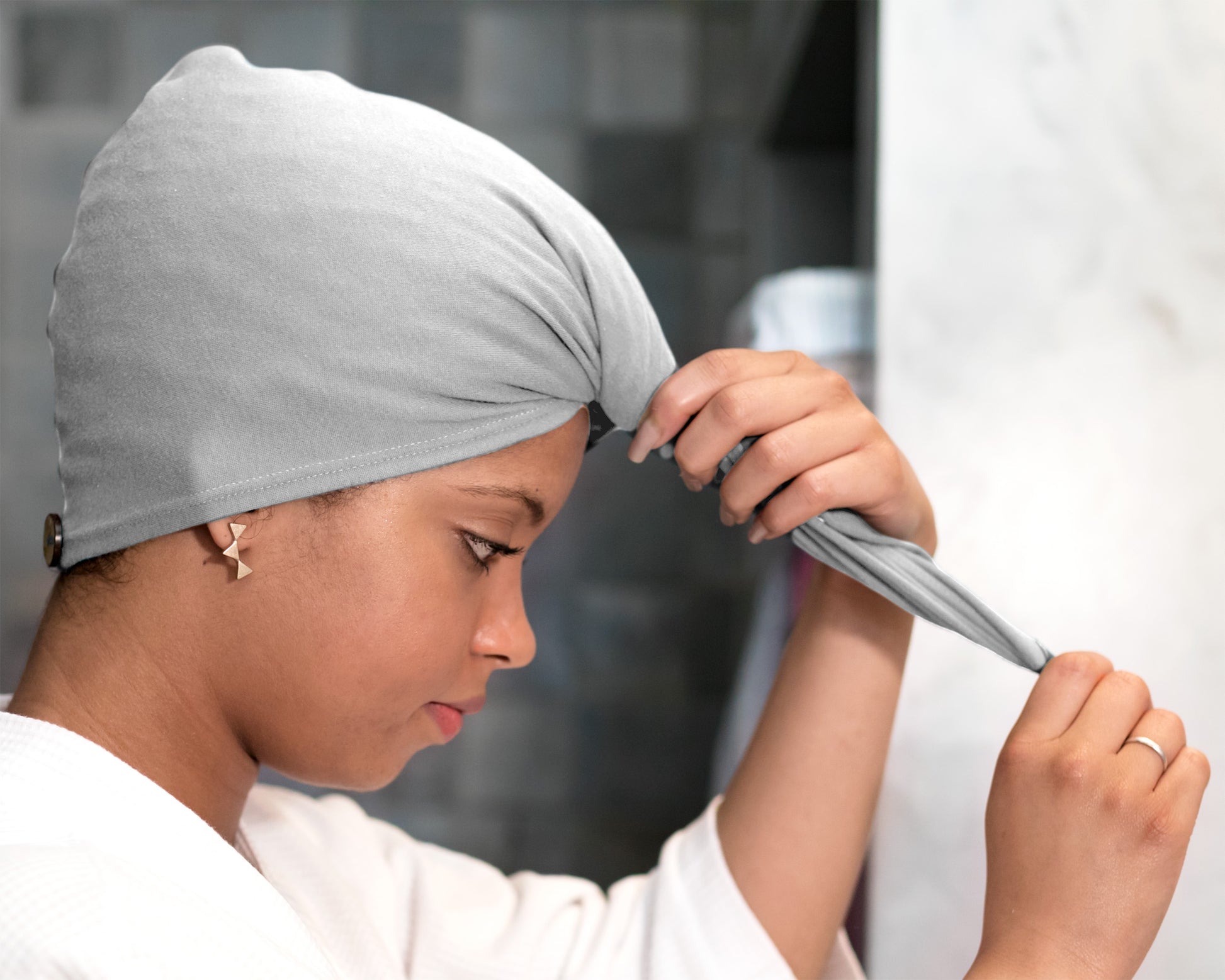Woman adjusting a T-Shirt Hair Towel Hood for Curly, Wavy, and Straight Hair - Soft, Absorbent, and Eco-Friendly in gray, in a bathroom setting