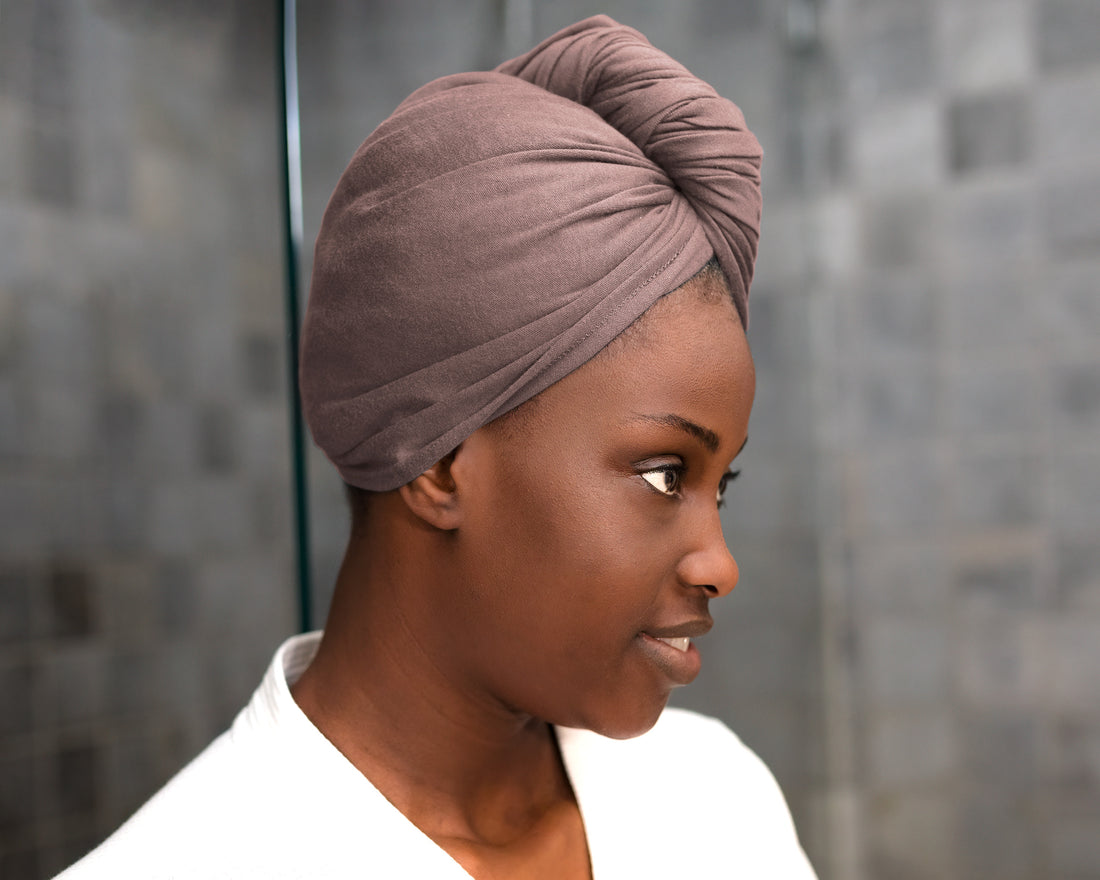 Woman wearing a Mocha eco-friendly hair towel, drying her hair for frizz-free results in a bathroom setting