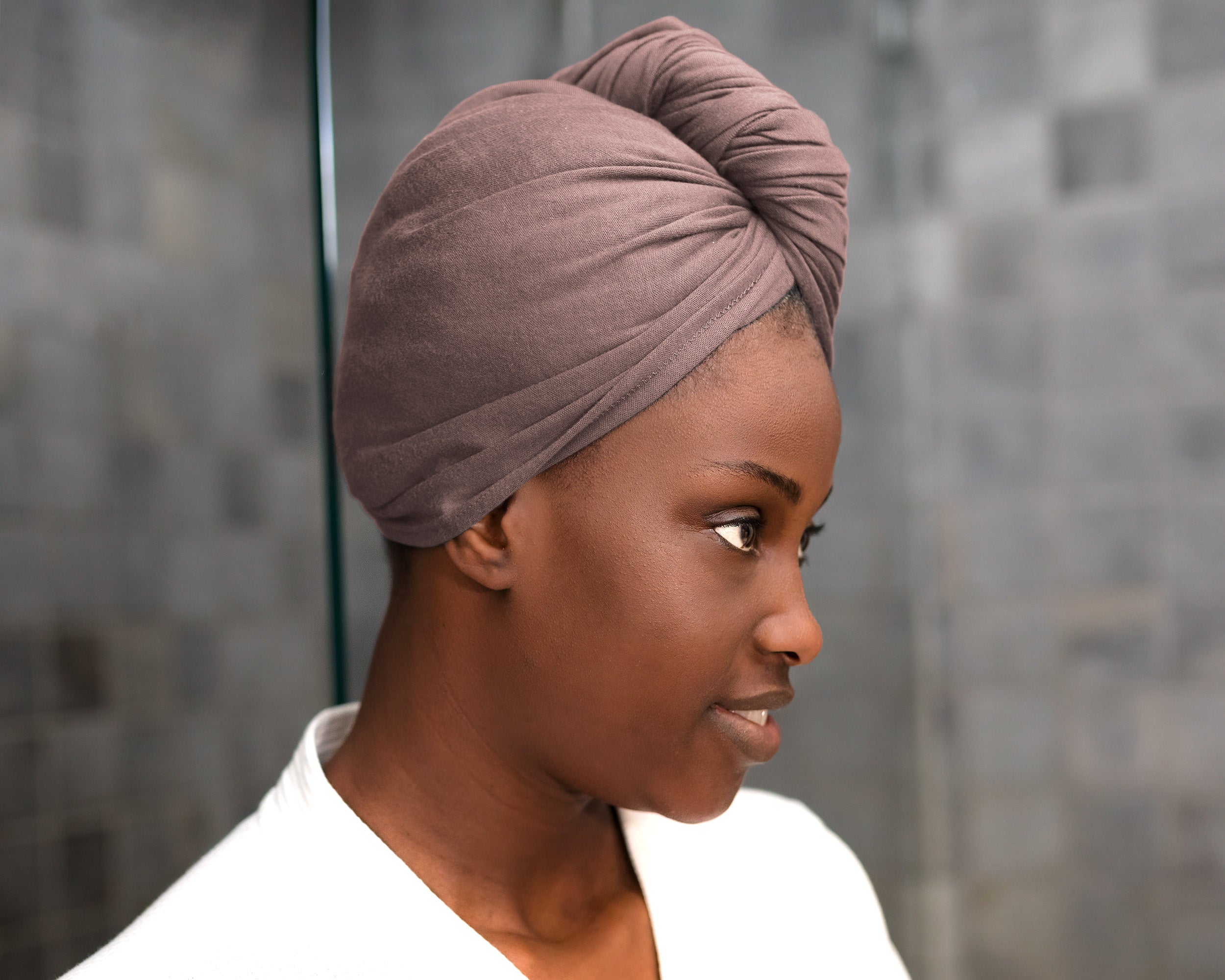 Woman wearing a Mocha eco-friendly hair towel, drying her hair for frizz-free results in a bathroom setting