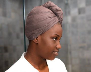 Woman wearing a Mocha eco-friendly hair towel, drying her hair for frizz-free results in a bathroom setting
