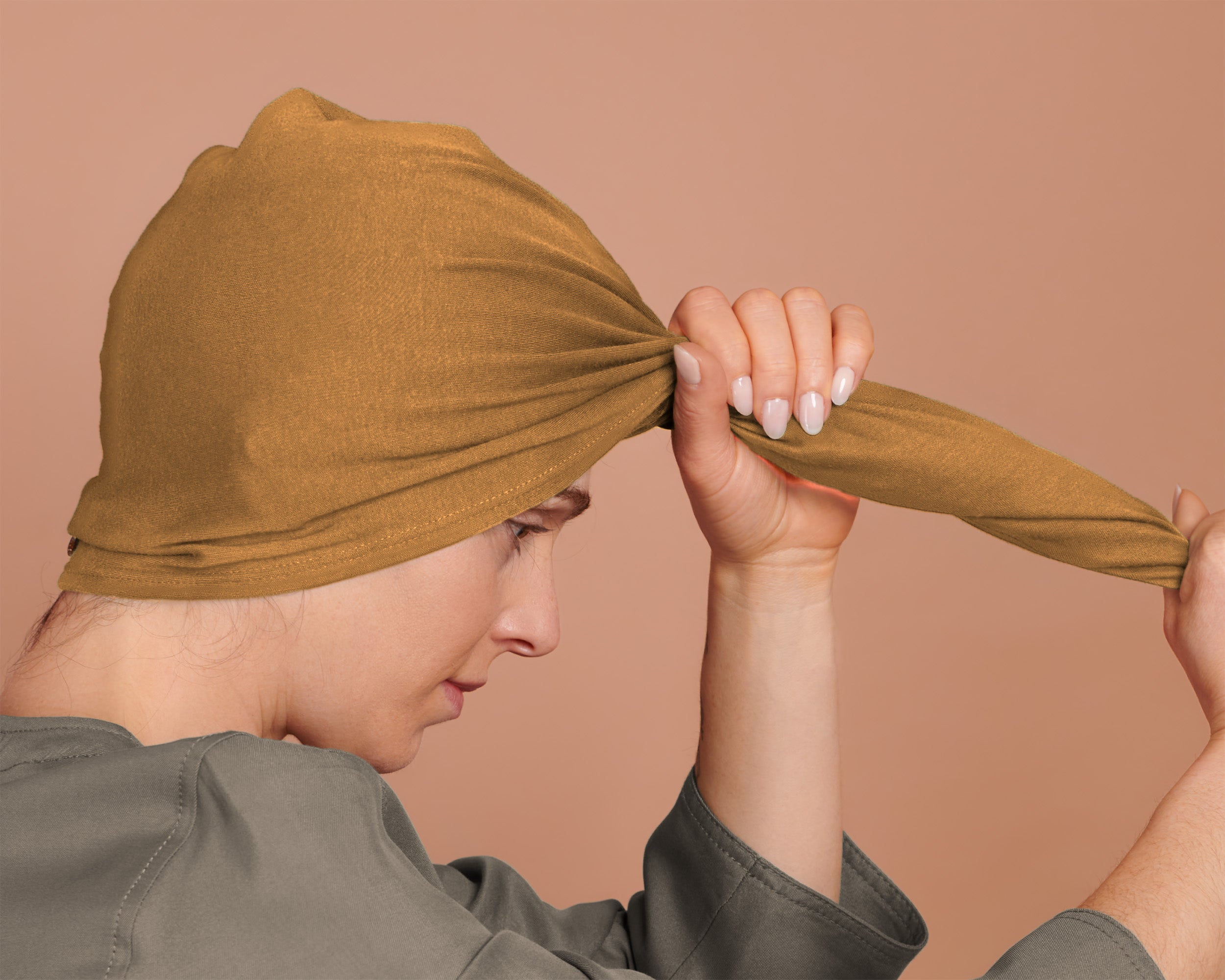 A person wearing a yellow t-shirt hair towel hood, tying it around their head.