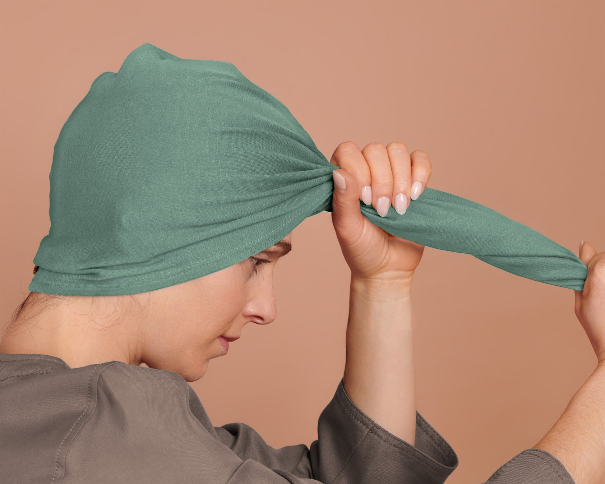woman using a T-Shirt Hair Towel Hood for Curly, Wavy, and Straight Hair - Soft, Absorbent, and Eco-Friendly in jade green, against a beige background