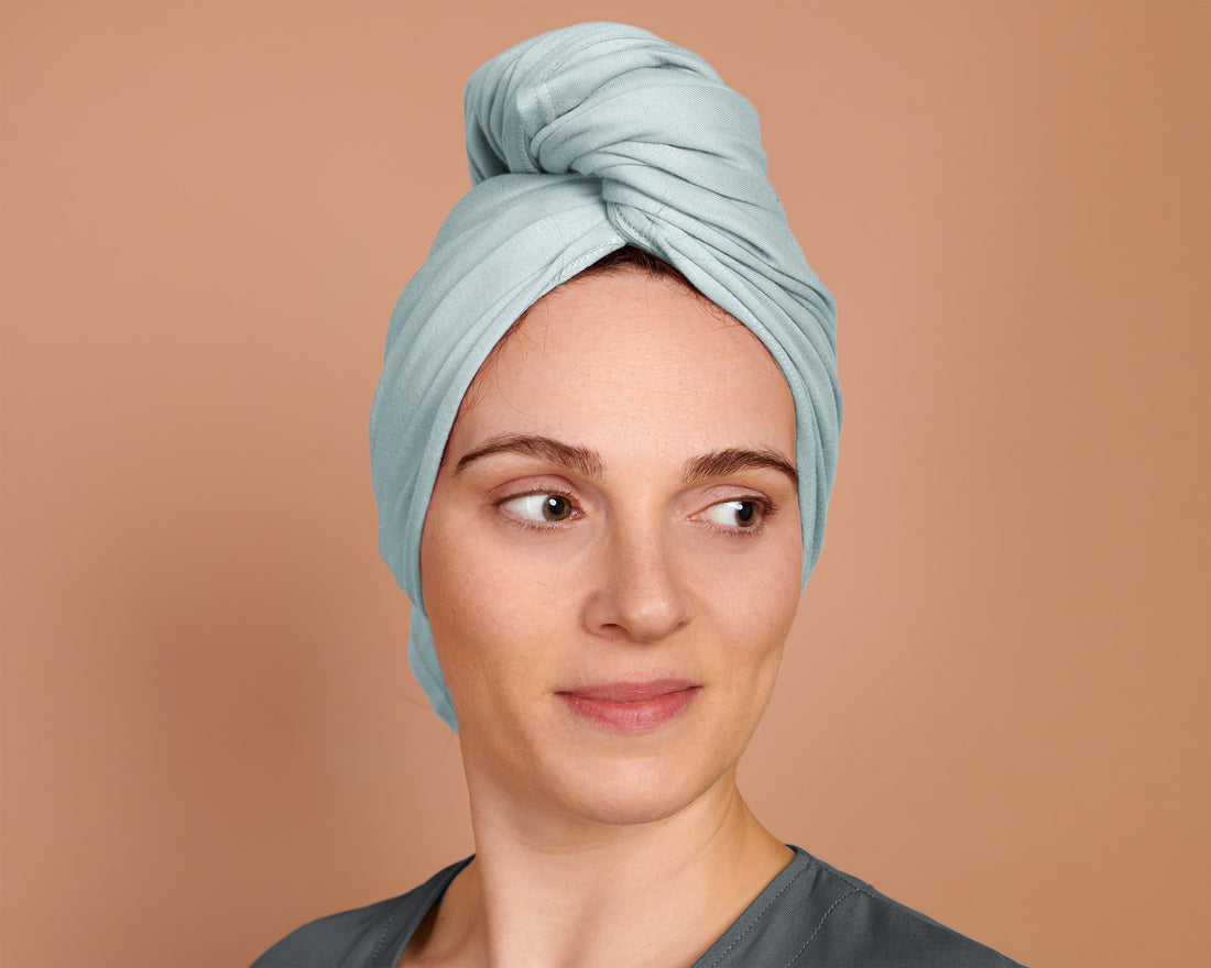 Woman with curly hair plopping a T-Shirt Hair Towel for Curly, Wavy, and Straight Hair - Soft, Absorbent, and Eco-Friendly in sky blue,  in a beige background