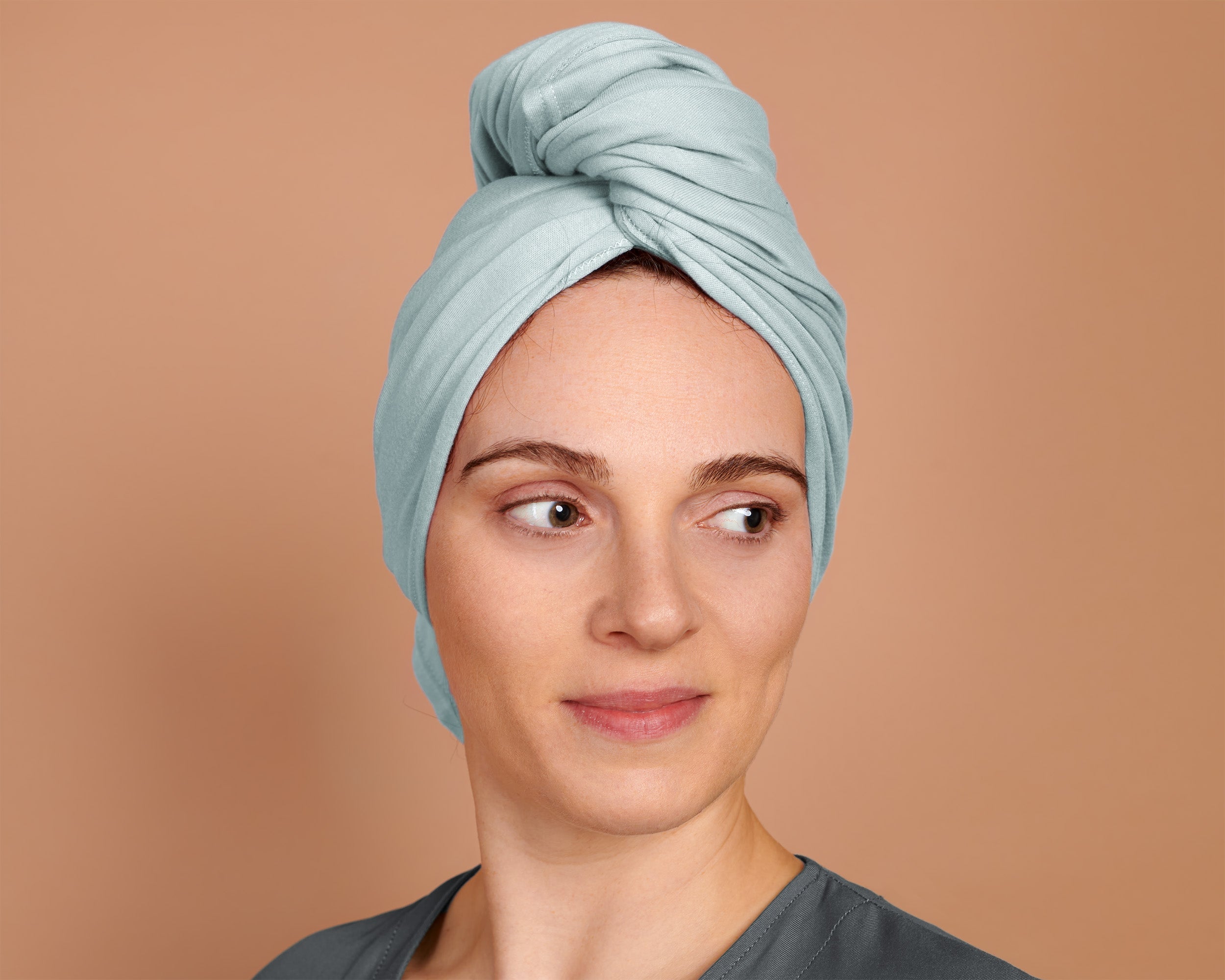 Woman with curly hair plopping a T-Shirt Hair Towel for Curly, Wavy, and Straight Hair - Soft, Absorbent, and Eco-Friendly in sky blue,  in a beige background