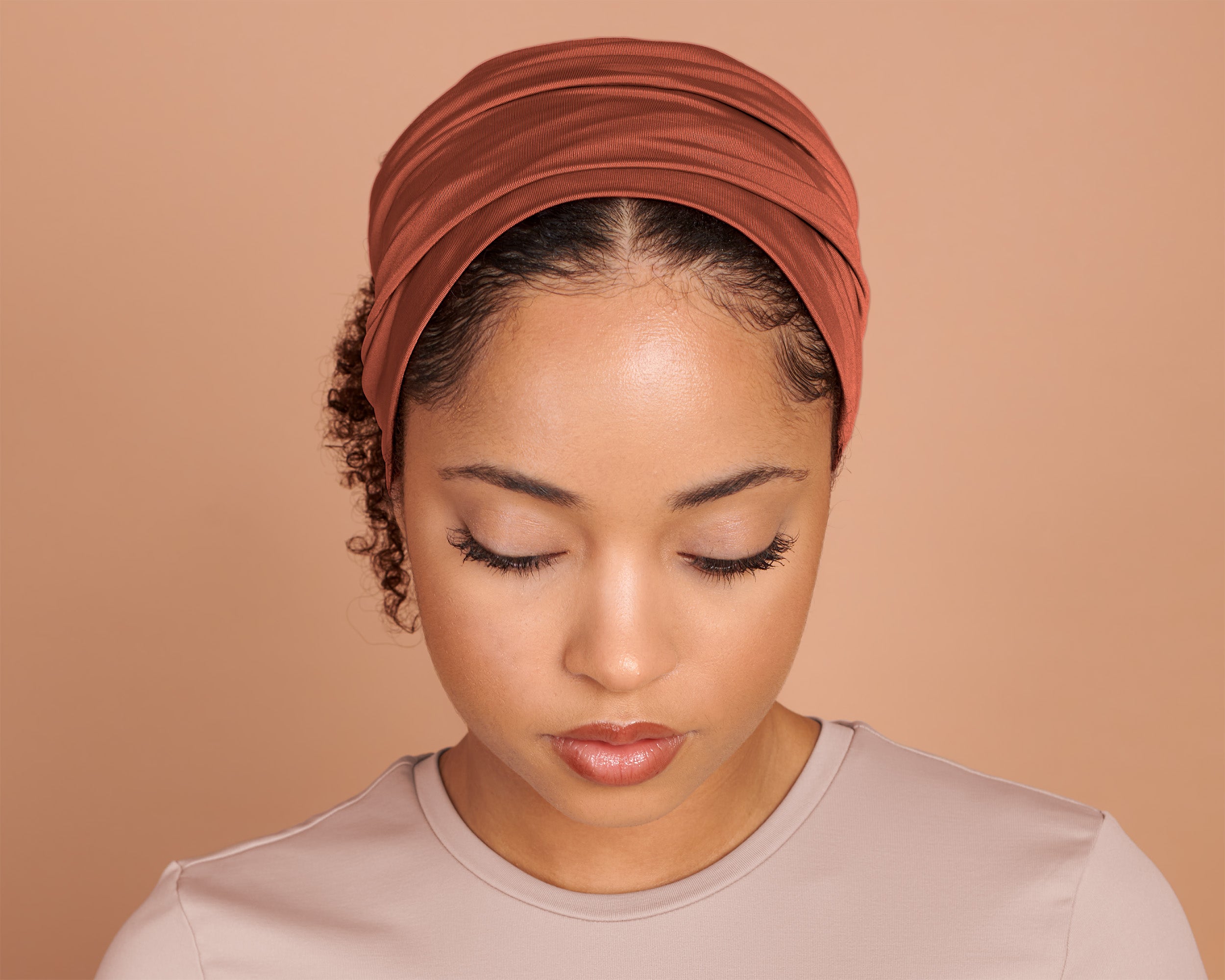 Woman wearing a Boho Headband Extra Wide in Burnt Orange, against a beige background