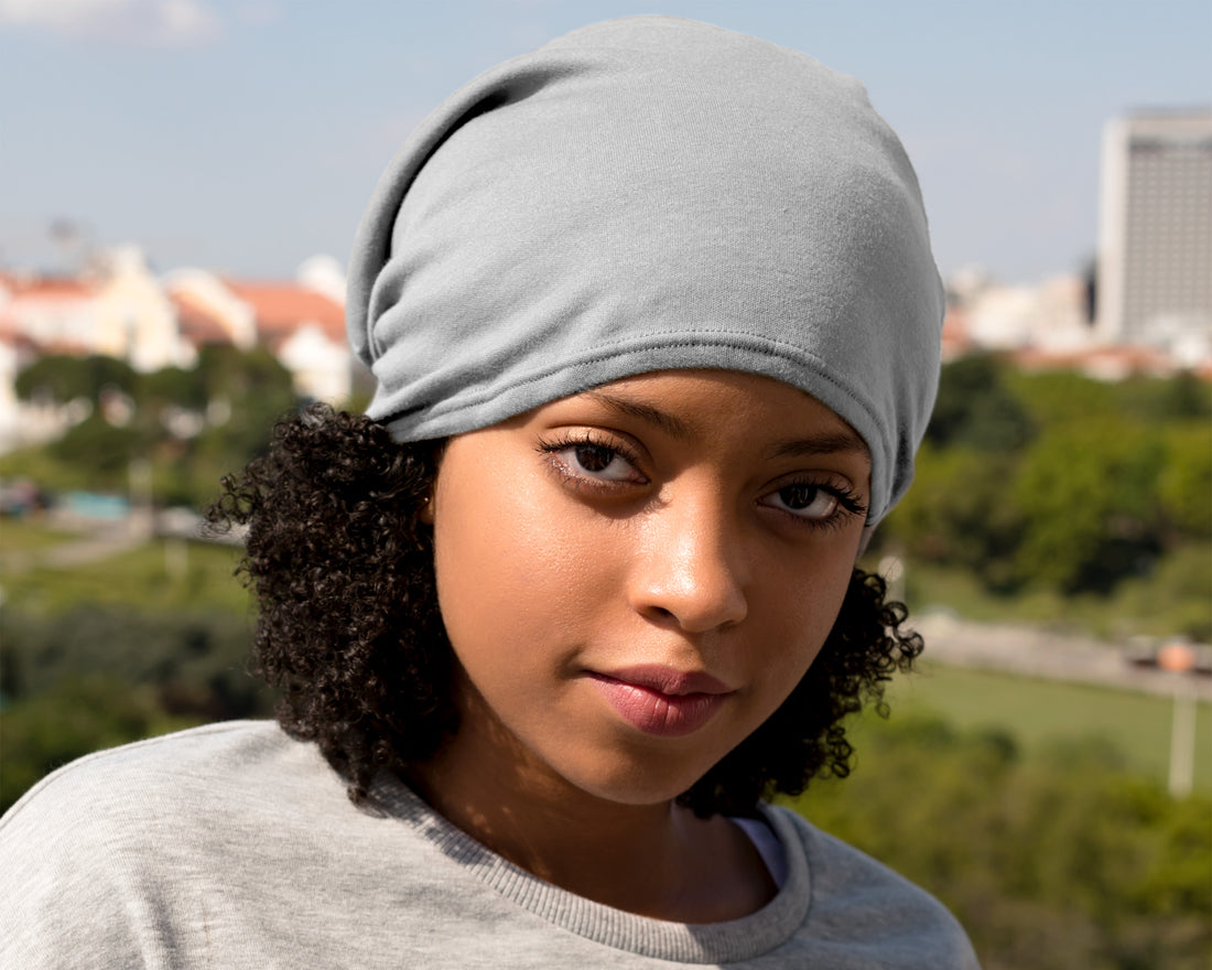Woman wearing a gray satin-lined beaniewith a blurred outdoor background