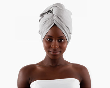 Woman wearing a gray T-Shirt Hair Towel for Curly, Wavy, and Straight Hair - Soft, Absorbent, and Eco-Friendly, wrapped around her head on a white background.